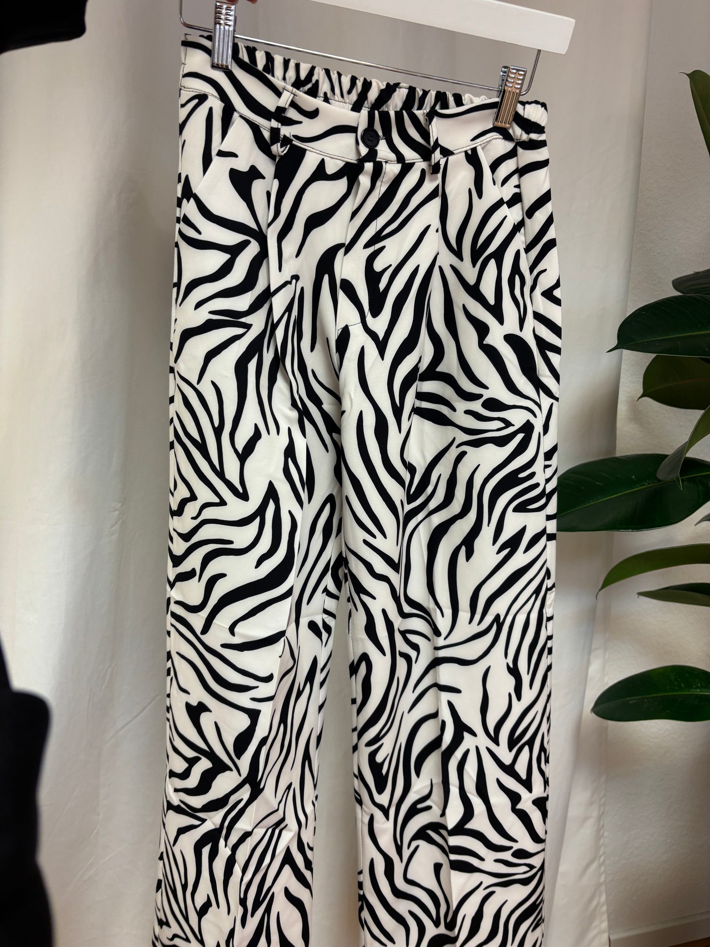 Weit geschnittene Damen-Zebrahose mit Bundfalten, flach auf weißem Hintergrund arrangiert