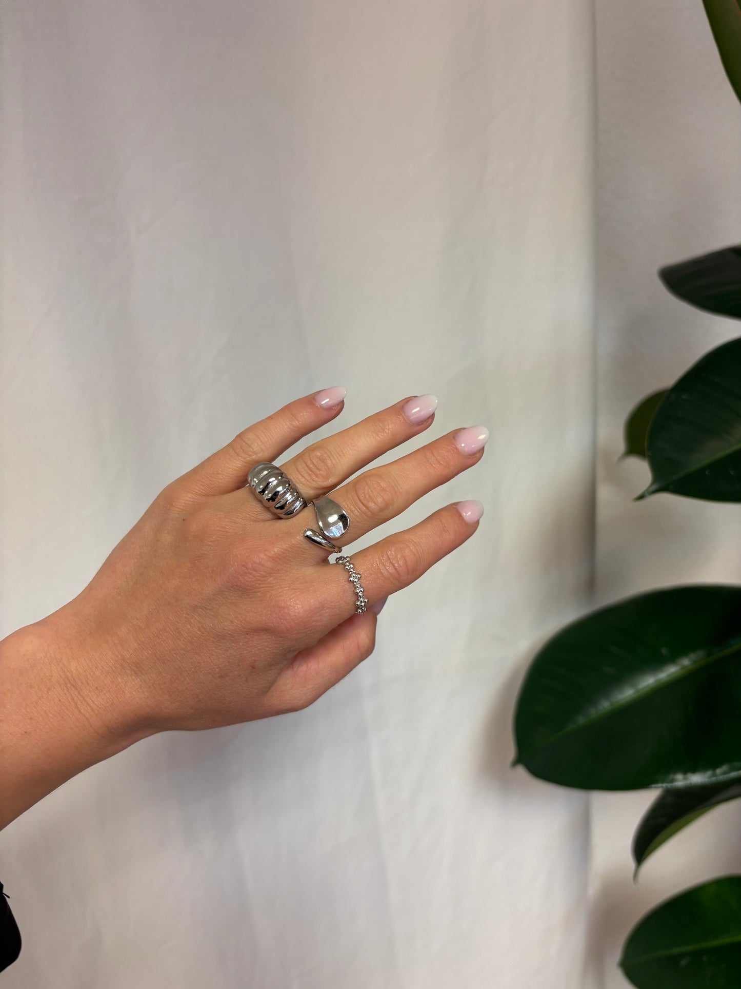 Muschelring aus Edelstahl am Finger getragen, glänzend und stilvoll kombiniert mit sommerlichem Look