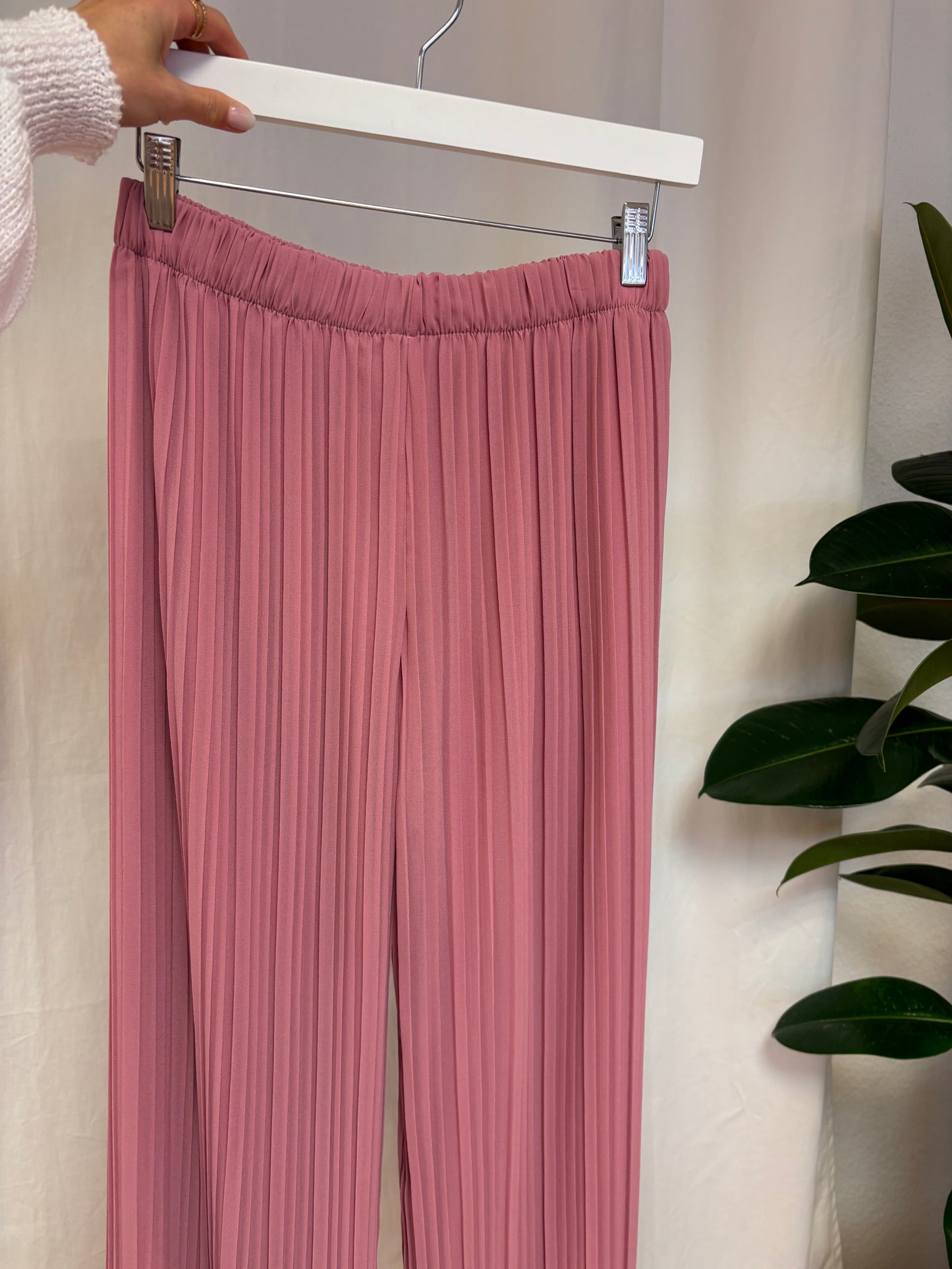 weitgeschnittene Plisseehose auf Bügel mit weisem Hintergrund für Frauen